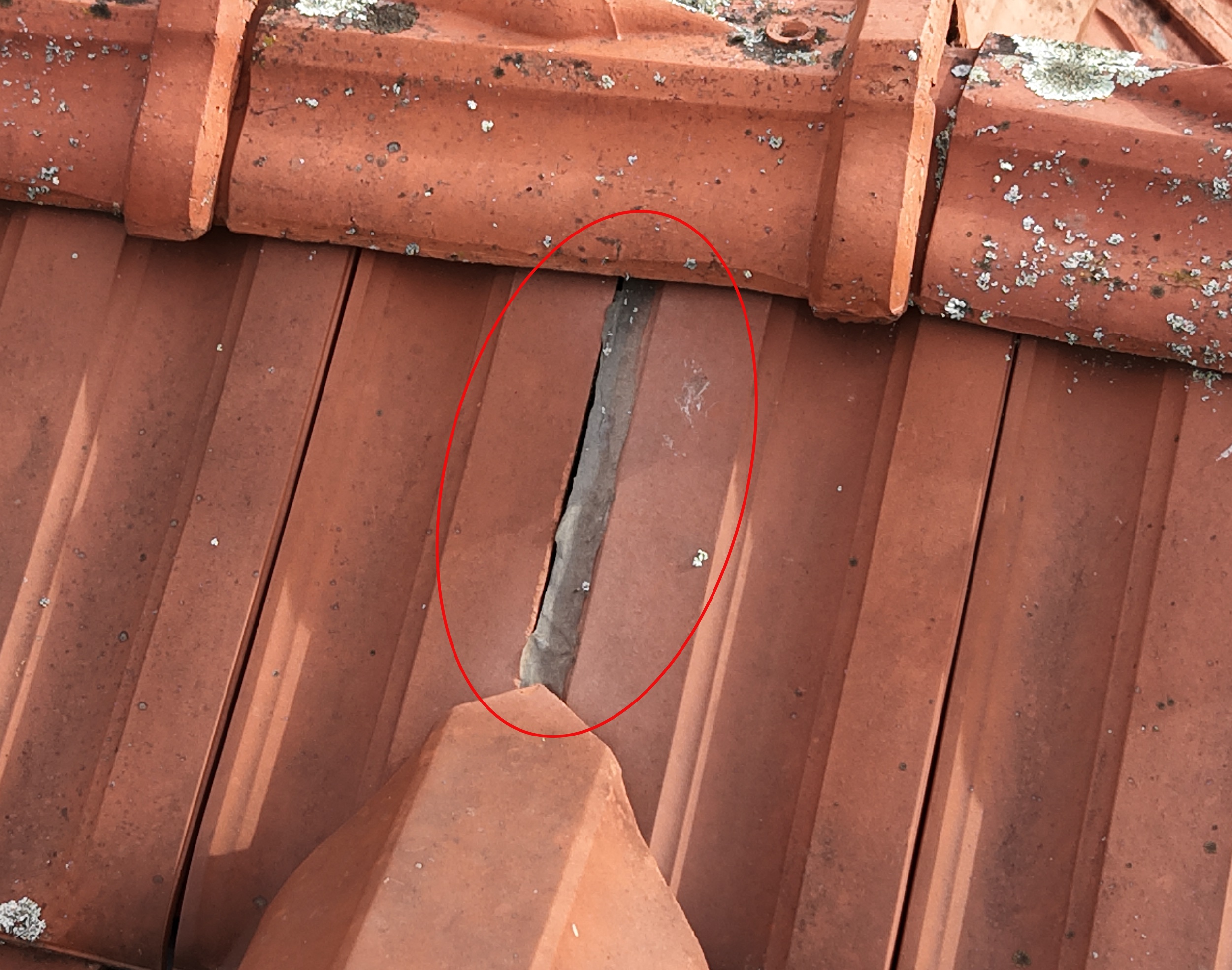 Vue rapprochée d’une toiture en tuiles montrant un espace visible entre deux éléments de couverture au niveau d’une jonction, mis en évidence pour inspection.